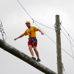 A MMA summer camper walks across a high ropes obstacle
