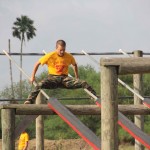 A camper slides down two poles on the combination obstacle